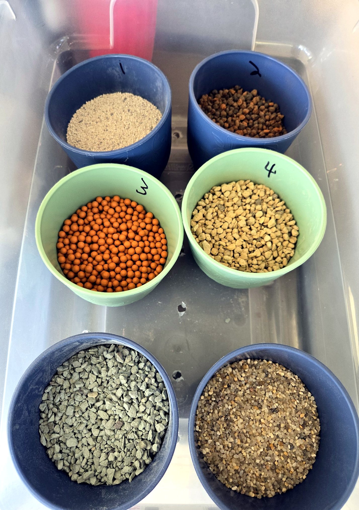 Numbered cups of the substrate trial materials in a clear tote, seen from above